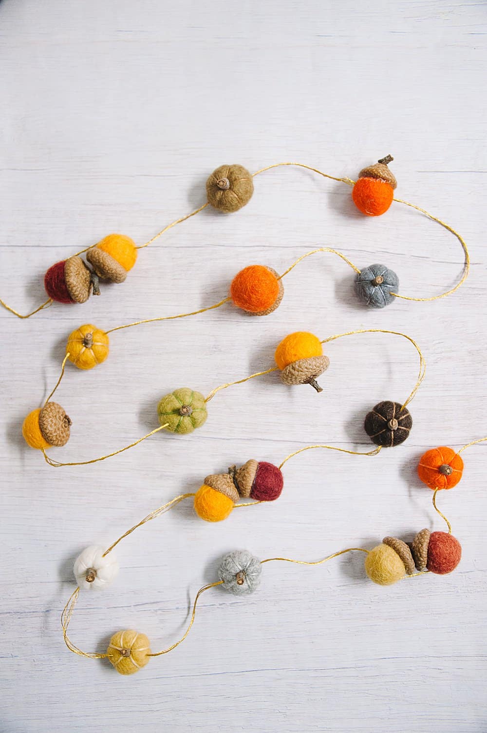 fall garland idea made with felt ball acorns and felt ball pumpkins.