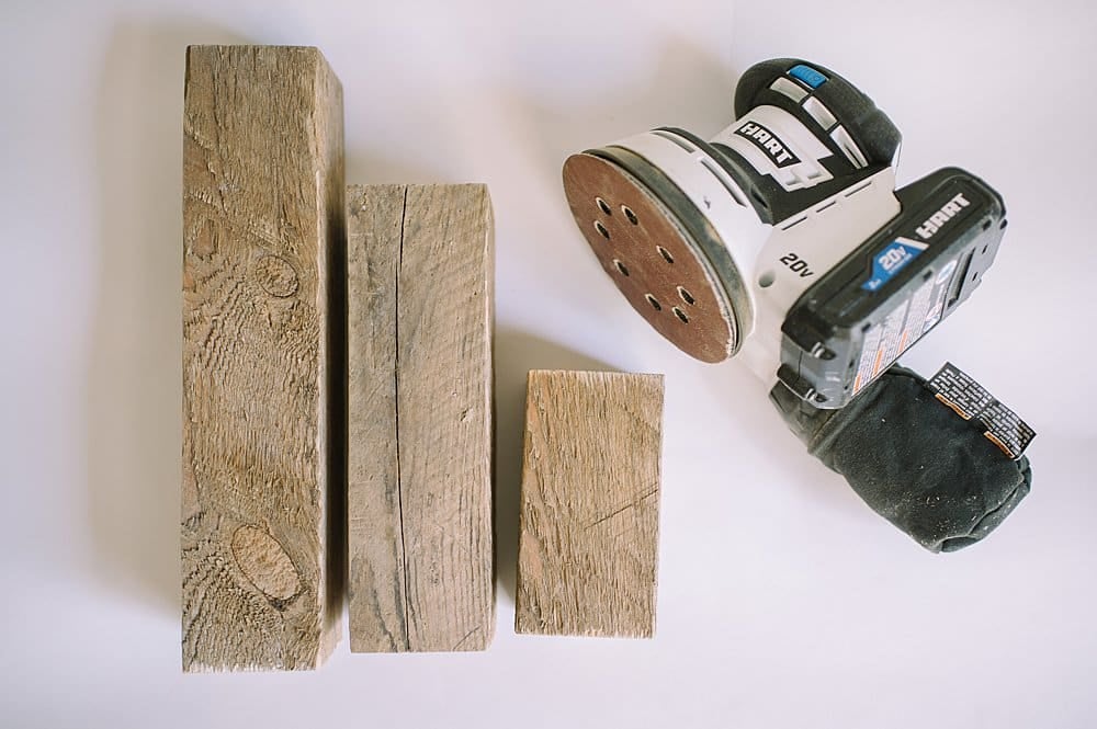 Wooden posts laying next to an orbital sander.
