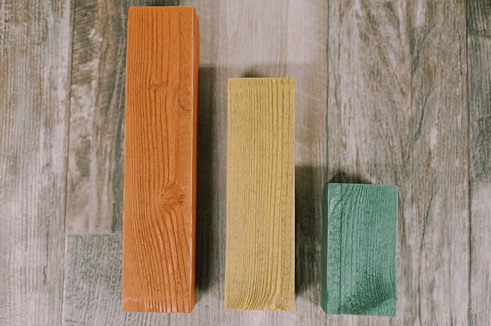Wooden blocks painted orange, yellow, and green, to make wooden pumpkins.