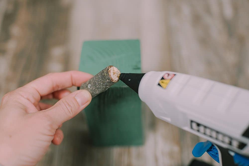 Hot gluing a stem onto top of wooden pumpkin.