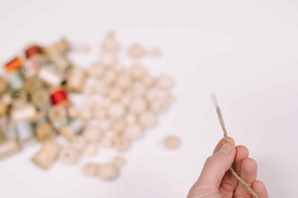 put tape on the end of twine to thread through wood beads