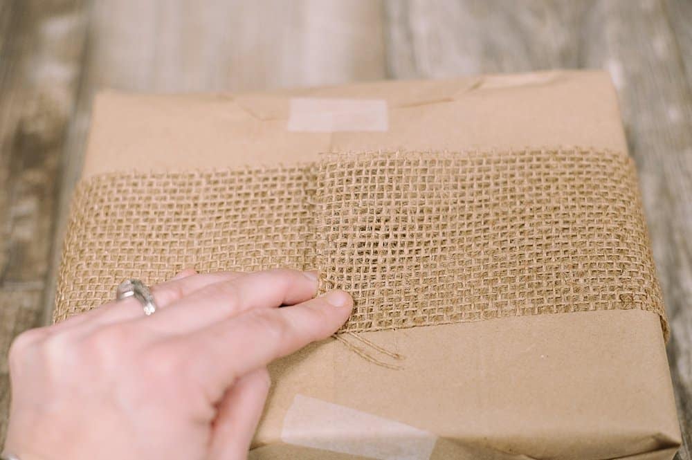 hot glue burlap ribbon on bottom of gift wrap to secure