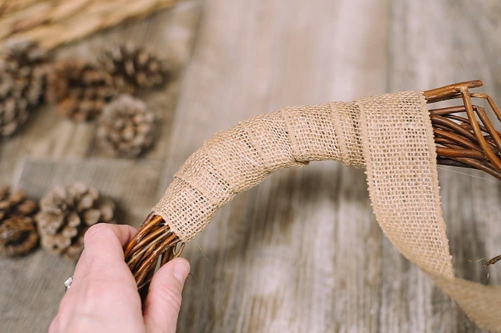 Wrap burlap ribbon around a grapevine wreath form.