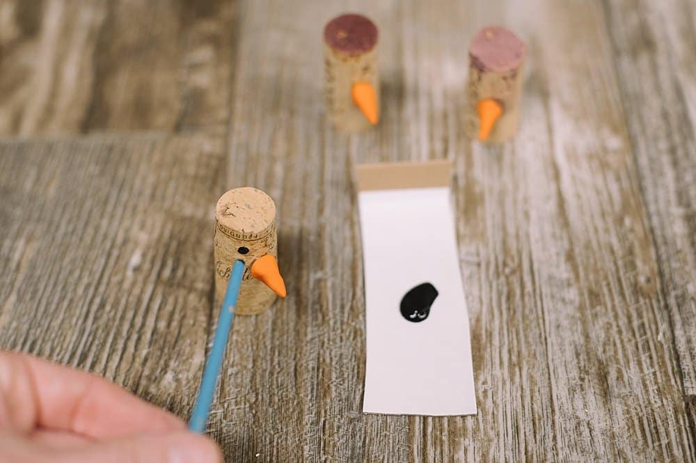 use wooden end of a small paintbrush to dab black dots onto the cork for eyes and a smile