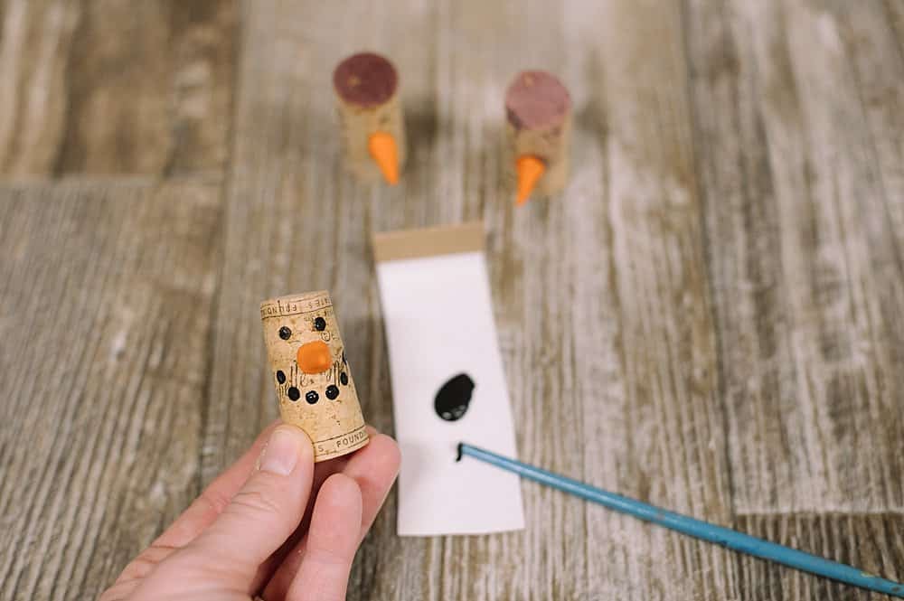 use wooden end of a small paintbrush to dab black dots onto the cork for eyes and a smile