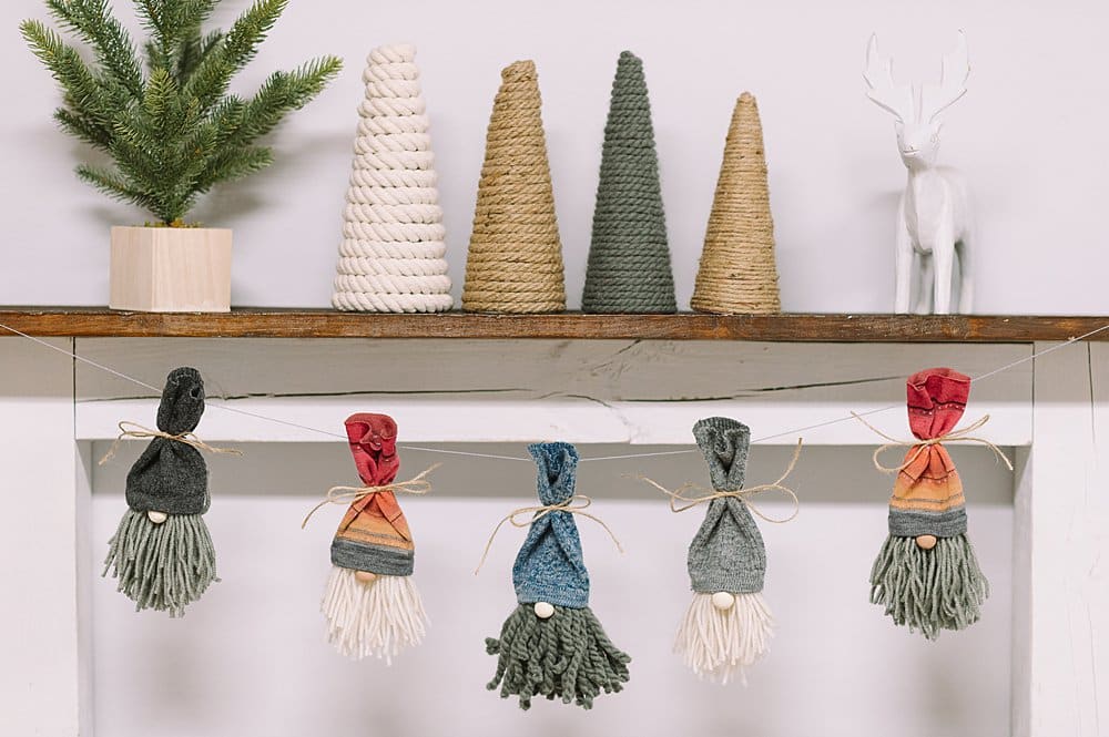 A yarn and sock gnome garland hanging on the mantel.