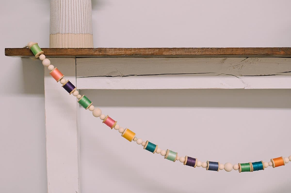 A DIY Colorful Garland for your Mantel with Vintage Wooden Spools of Thread and Wood Beads.