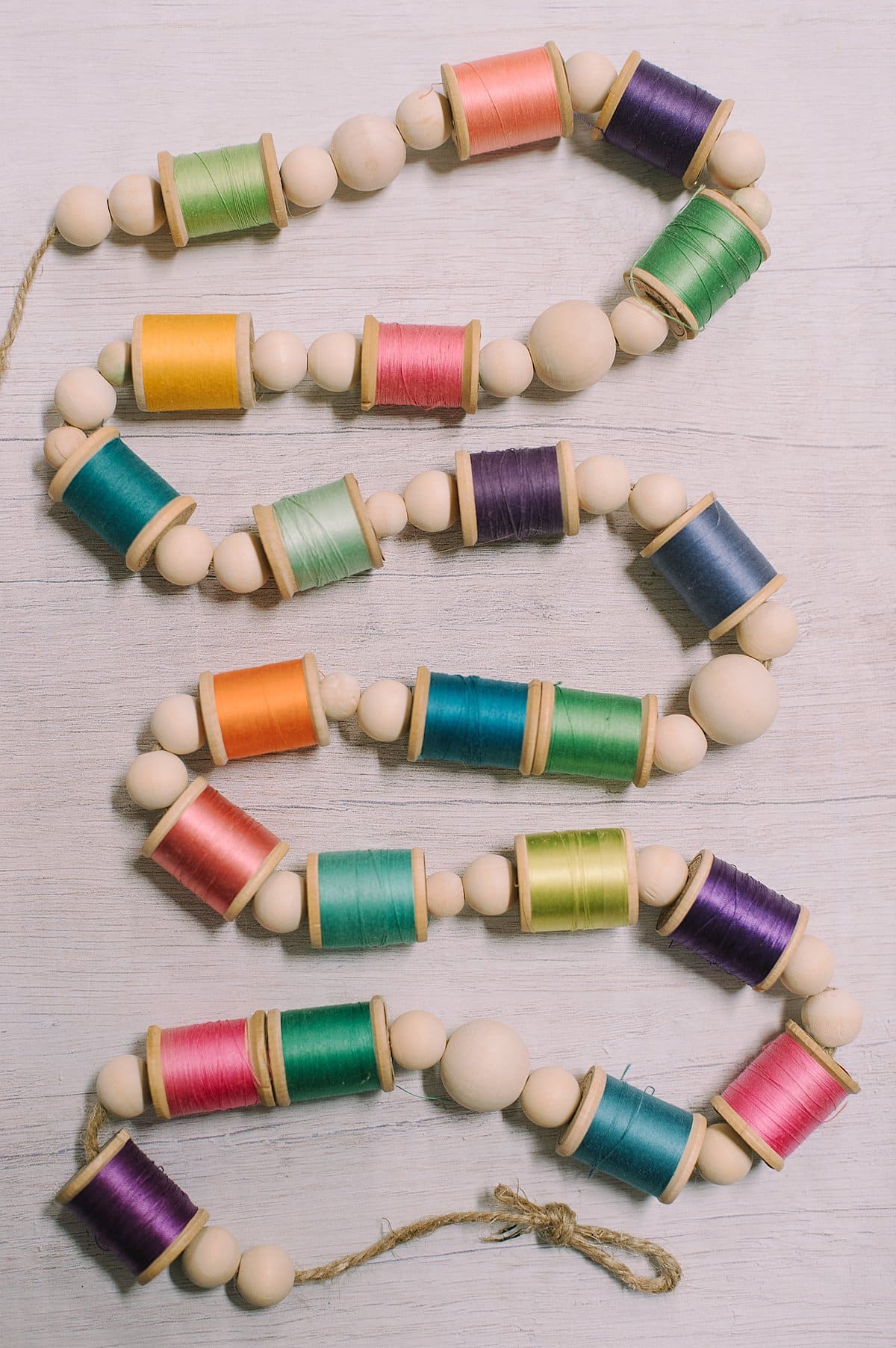 A colorful summer garland with wood beads and bright, colorful thread spools.