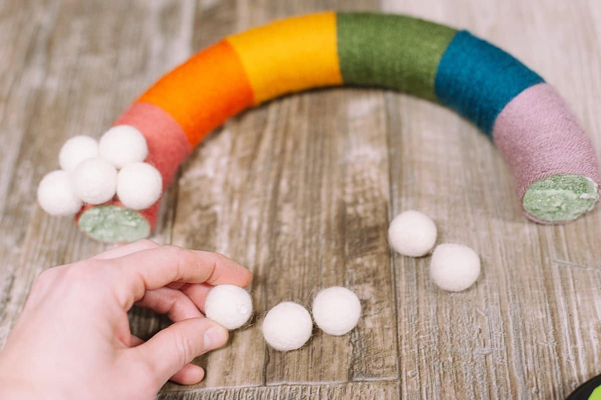 hot glue felt balls to the bottoms of the wreath to make clouds for the rainbow