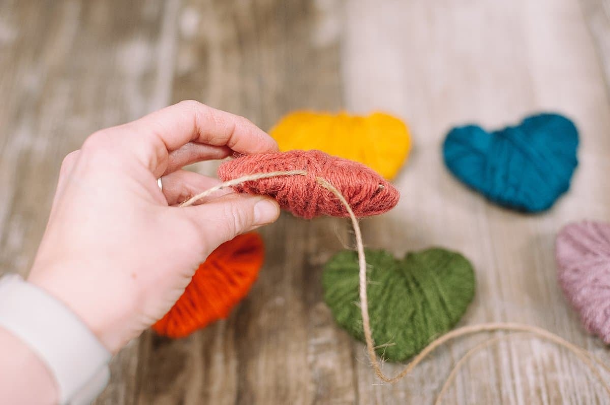 Thread yarn heart onto twine.