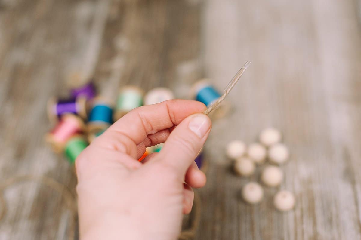 Tape the end of the twine to make it easier to thread into the wooden beads and spools of thread.