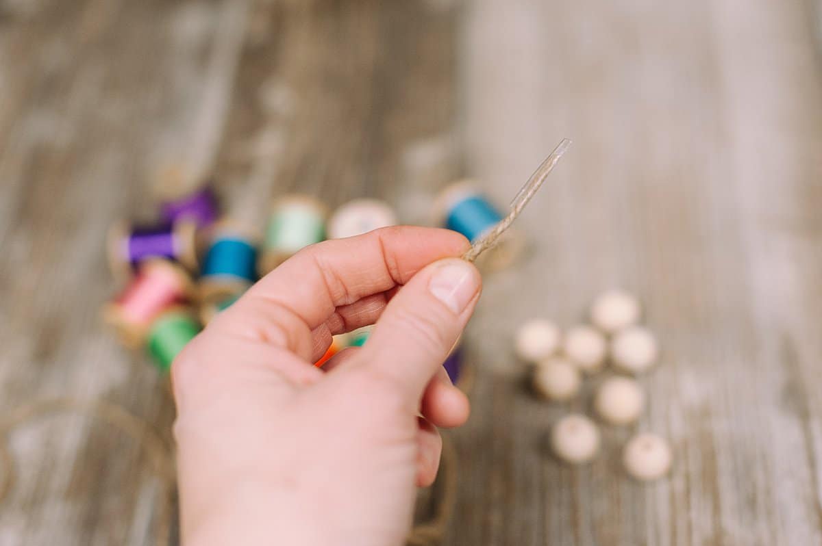 tape the end of the twine to make it easier to thread into the wooden beads and spools of thread