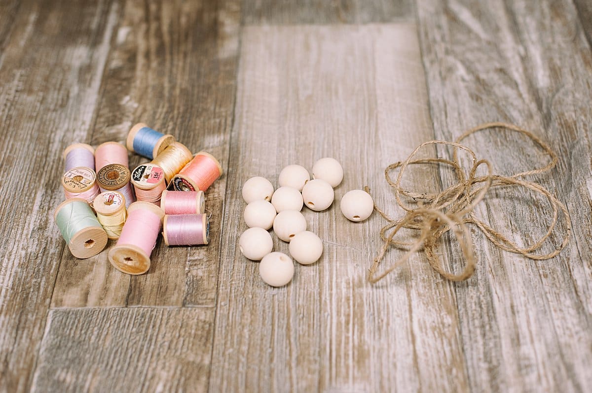 Supplies to make a garland for spring with wooden beads and vintage pastel thread spools.