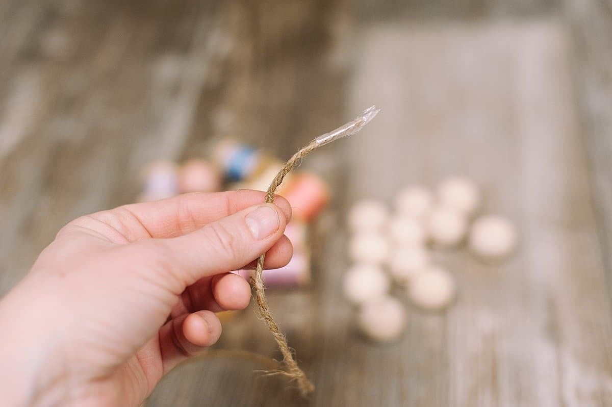 Use tape around the end of the twine to make it easier to thread on the wood beads and spools of thread.