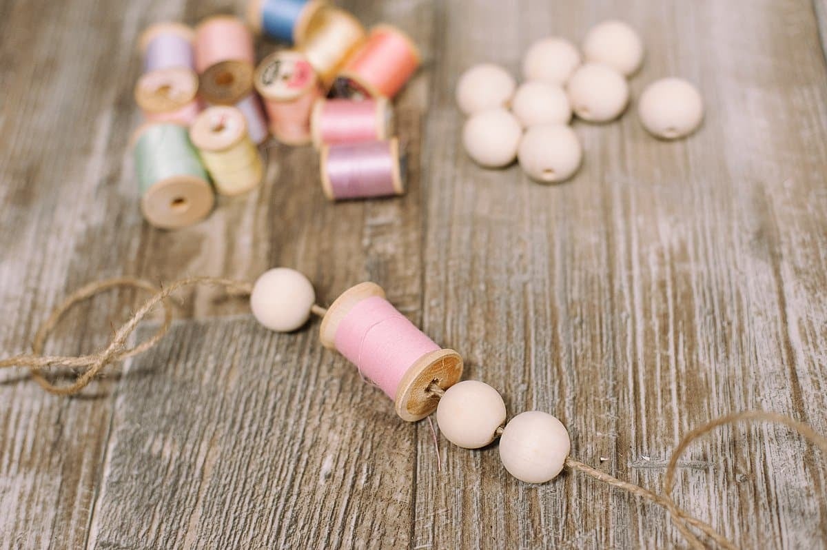 Continue adding wooden beads and spools of thread to your garland.