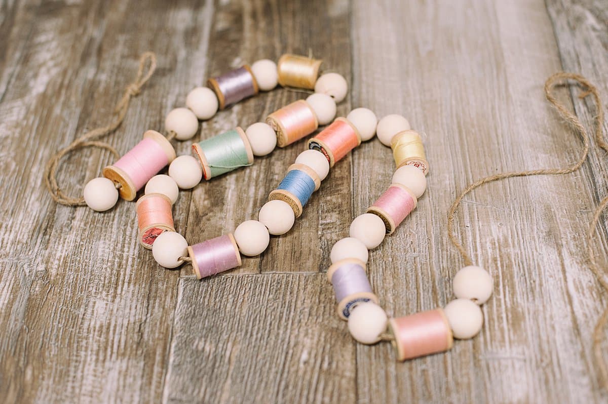 A spring garland with wood beads and thread spools on it.