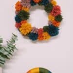 How to make a pom pom wreath using yarn in rainbow colors.