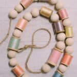 How to make a spring garland with wooden beads and pastel thread spools.