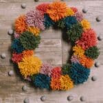 How to make a pom pom wreath using yarn in rainbow colors.