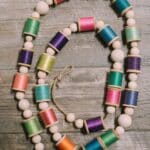 How to make a colorful garland with wood beads and thread spools.
