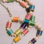 How to make a colorful garland with wood beads and thread spools.