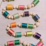 How to make a colorful garland with wood beads and thread spools.