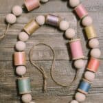 How to make a spring garland with wooden beads and pastel thread spools.