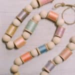 How to make a spring garland with wooden beads and pastel thread spools.