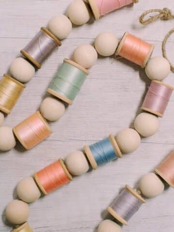 How to make a spring garland with wooden beads and pastel thread spools.