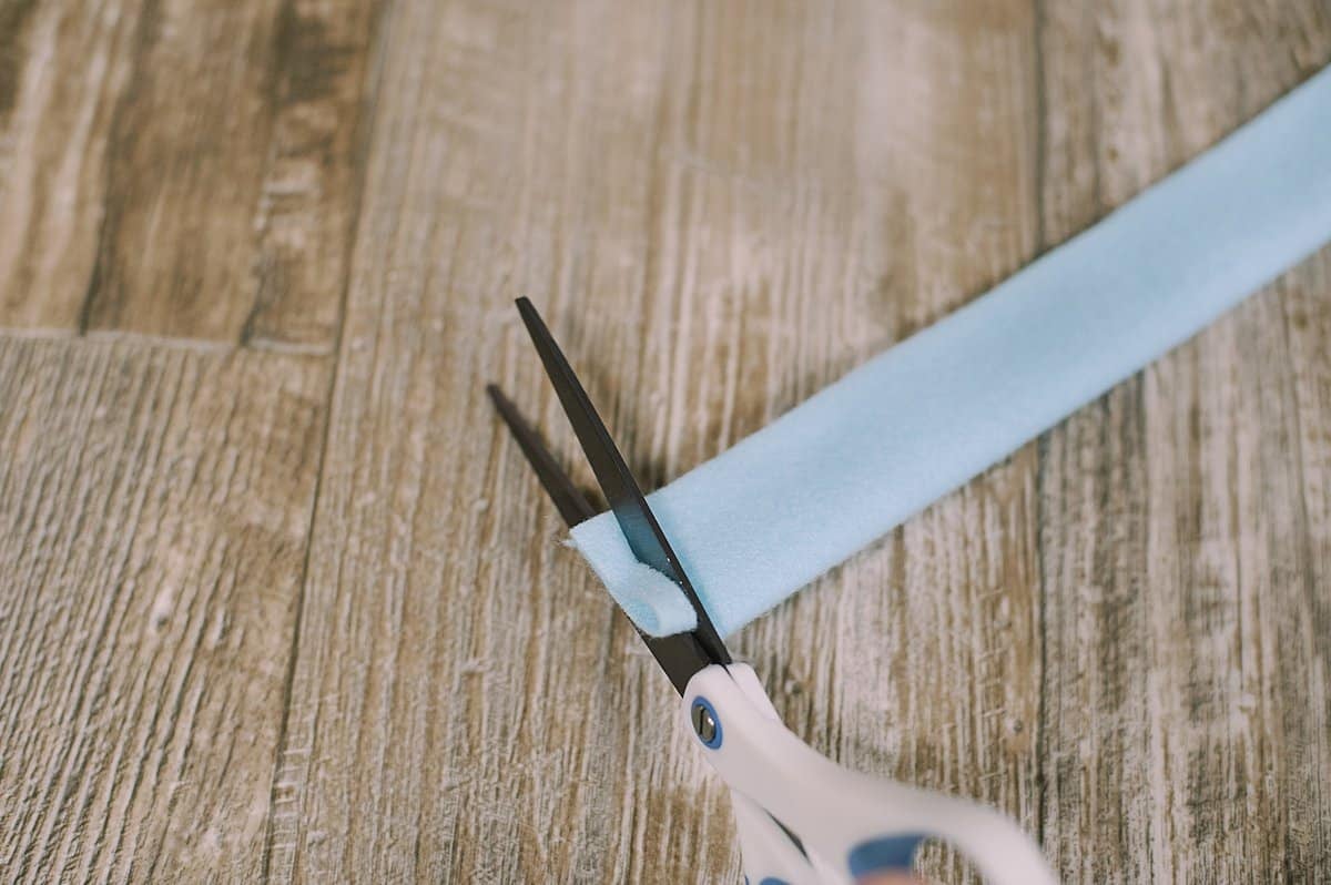 A strip of felt and a scissors cutting fringe along the bottom.