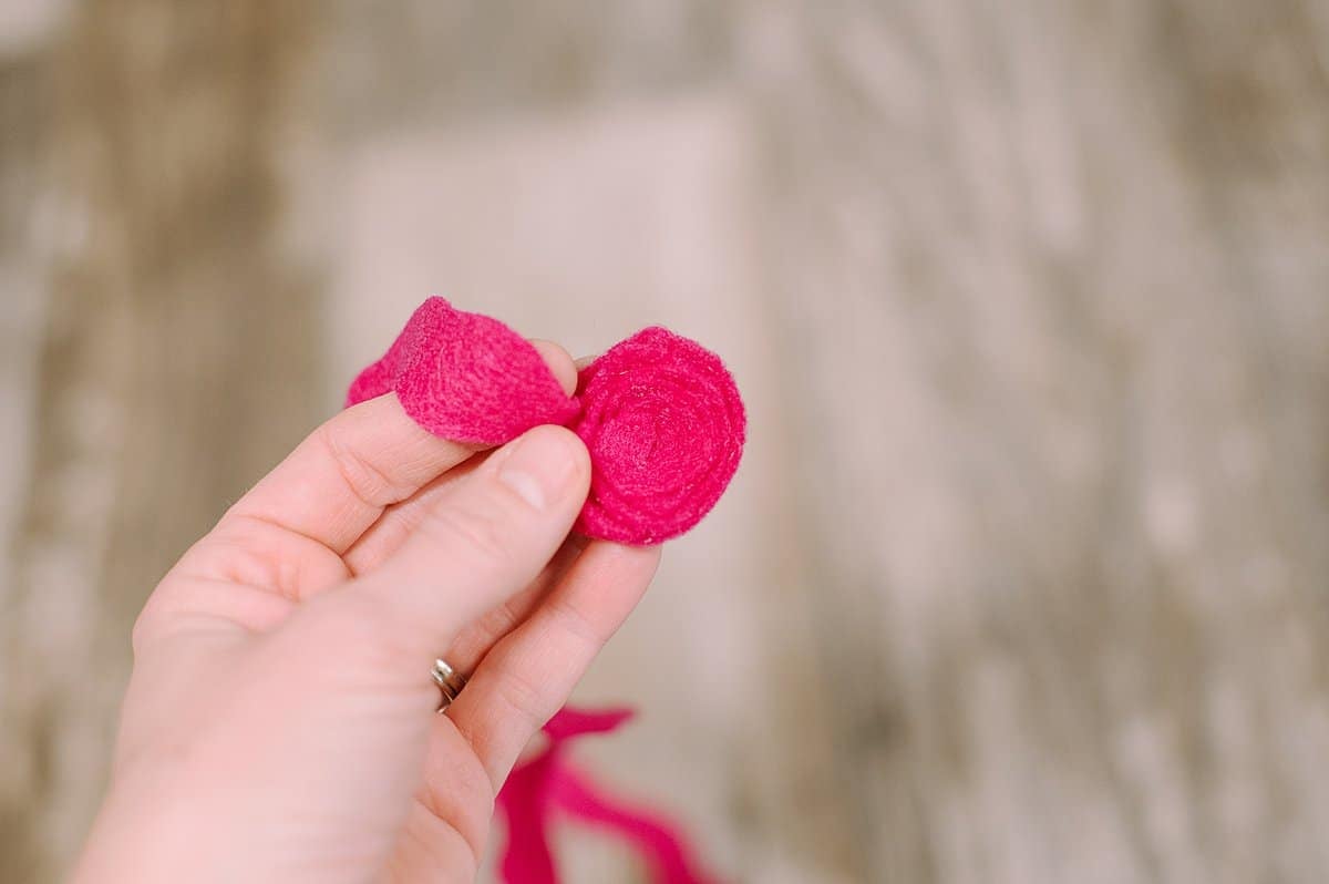 A hand holding and gluing the felt into a rosette shape.