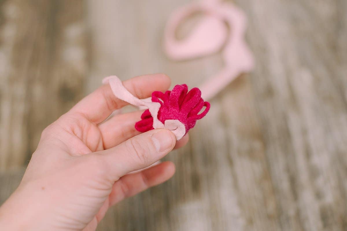 The bottom of a felt flower being hot glued in place onto a felt mum center.