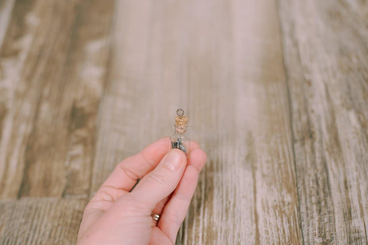 screw loop into the top of the cork in the glass jar