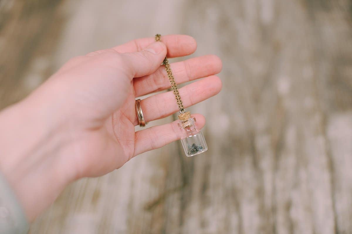 small glass jar necklace with sharks teeth inside