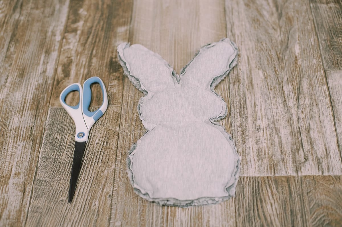 A fabric bunny shape and a pair of scissors laying next to it.