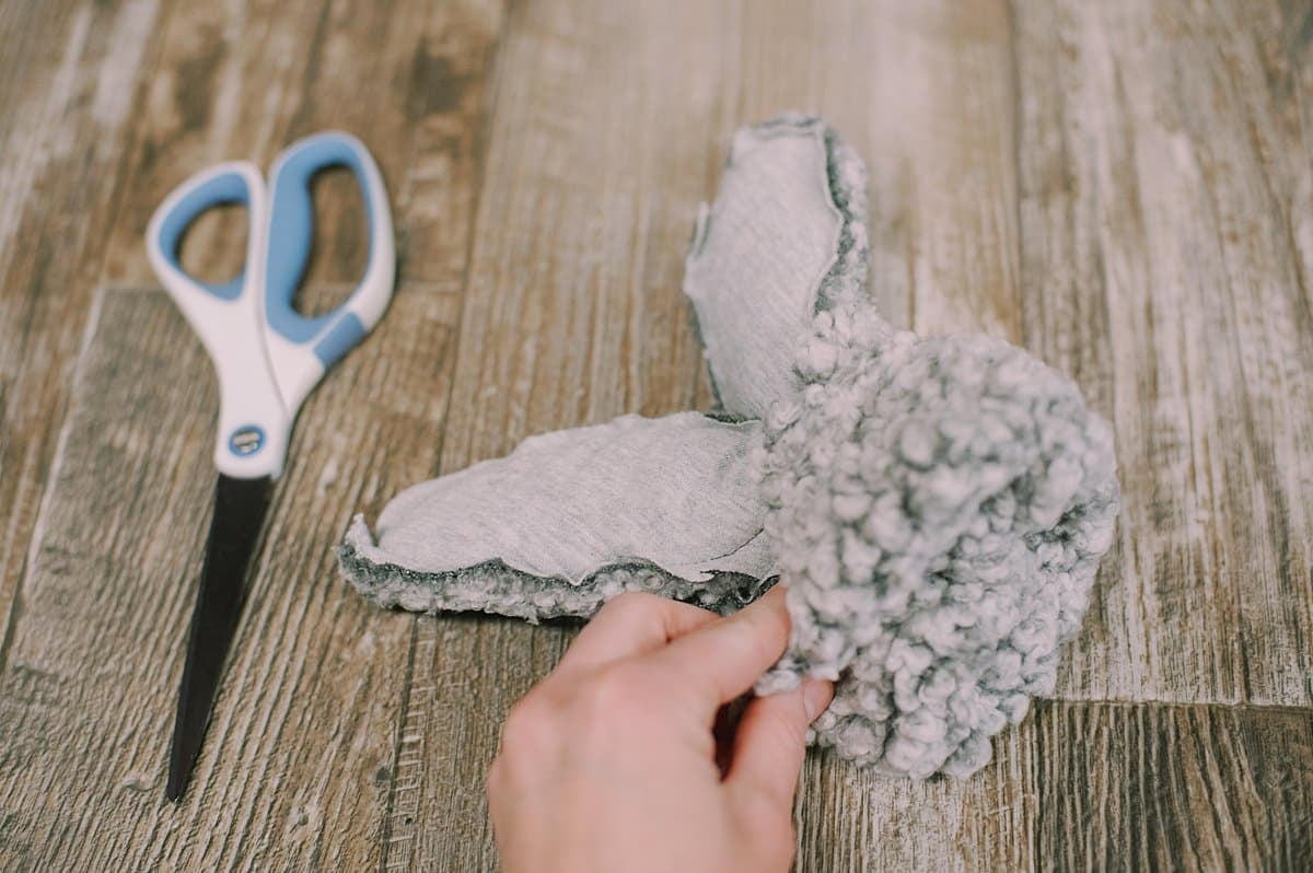 A hand turning a fabric bunny rightside out while a pair of scissors lays next to it.