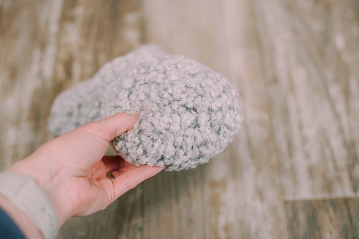 A hand holding the bottom of a DIY stuffed bunny rabbit.