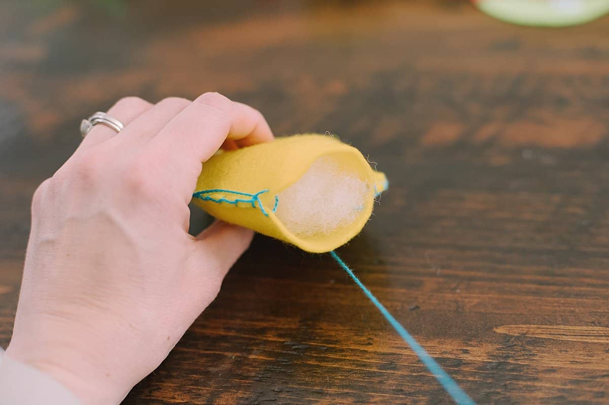 A hand holding a felt easter egg with poly-fil stuffing inside the egg shape.