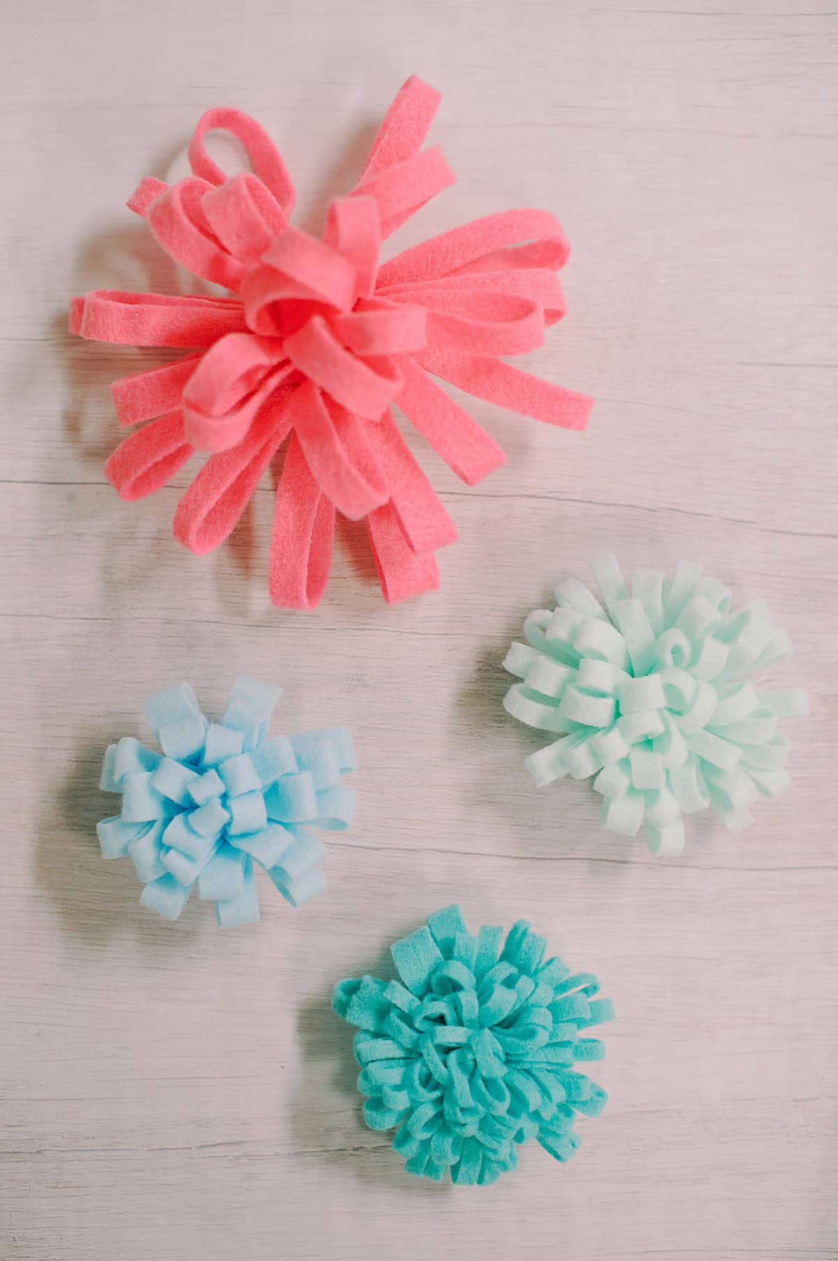 Various sizes of felt mum flowers made in pastel spring colors.