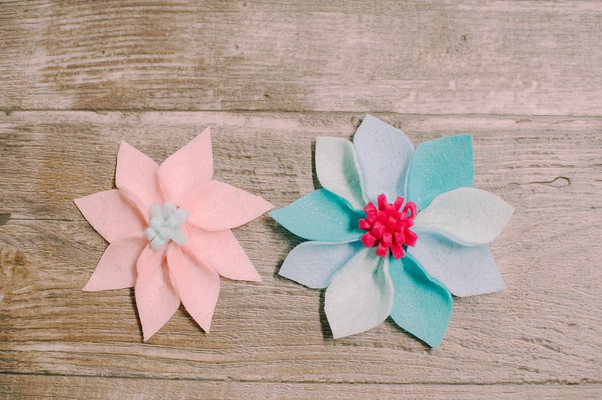 DIY felt petal flowers laying on a wooden surface.