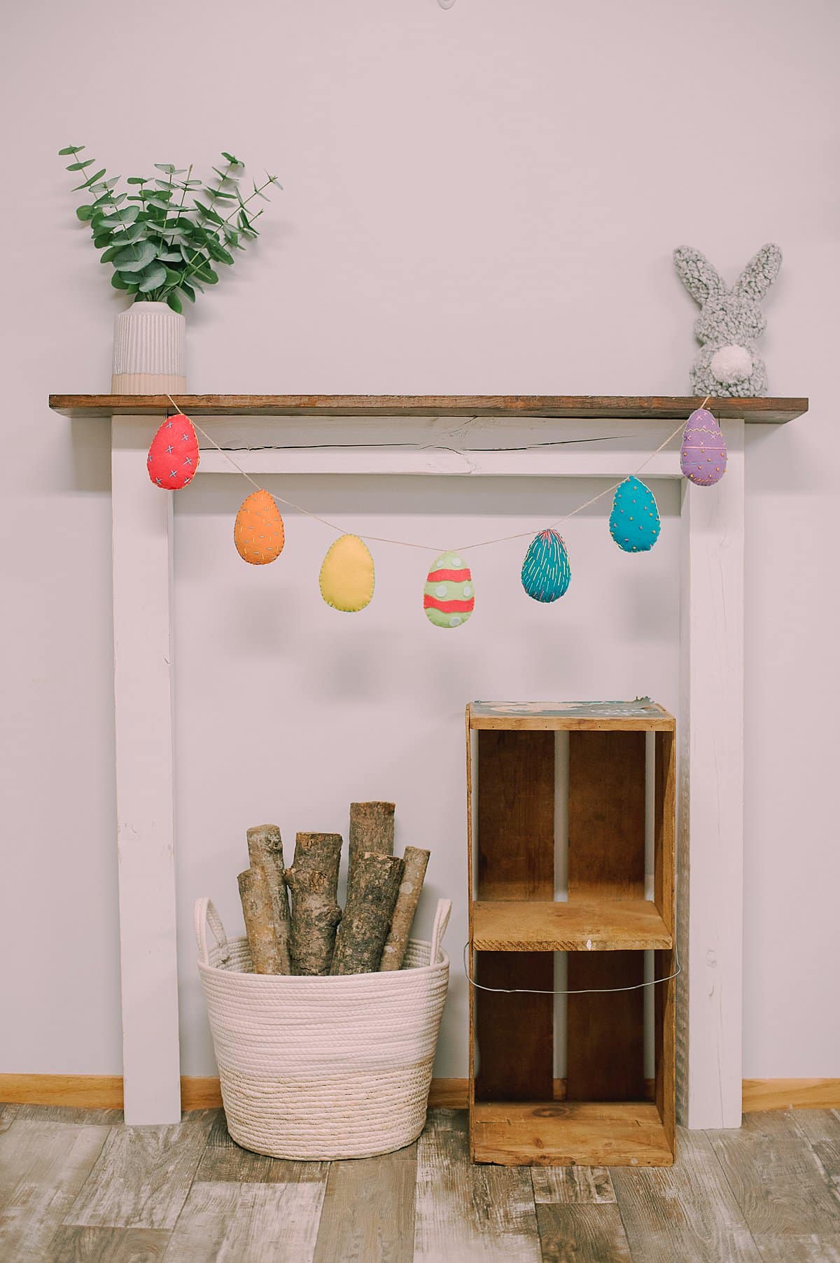 A felt egg garland hanging from a wood shelf.