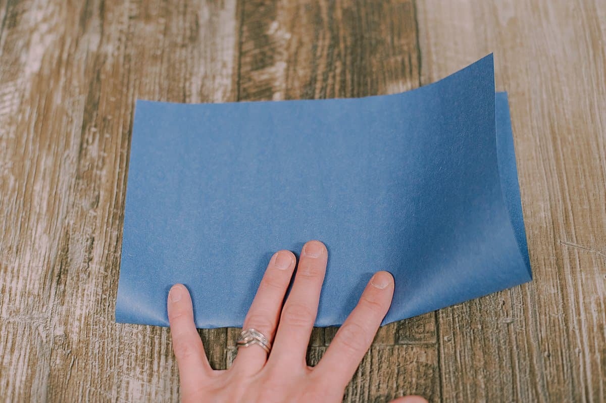 Blue construction paper being folded in half.