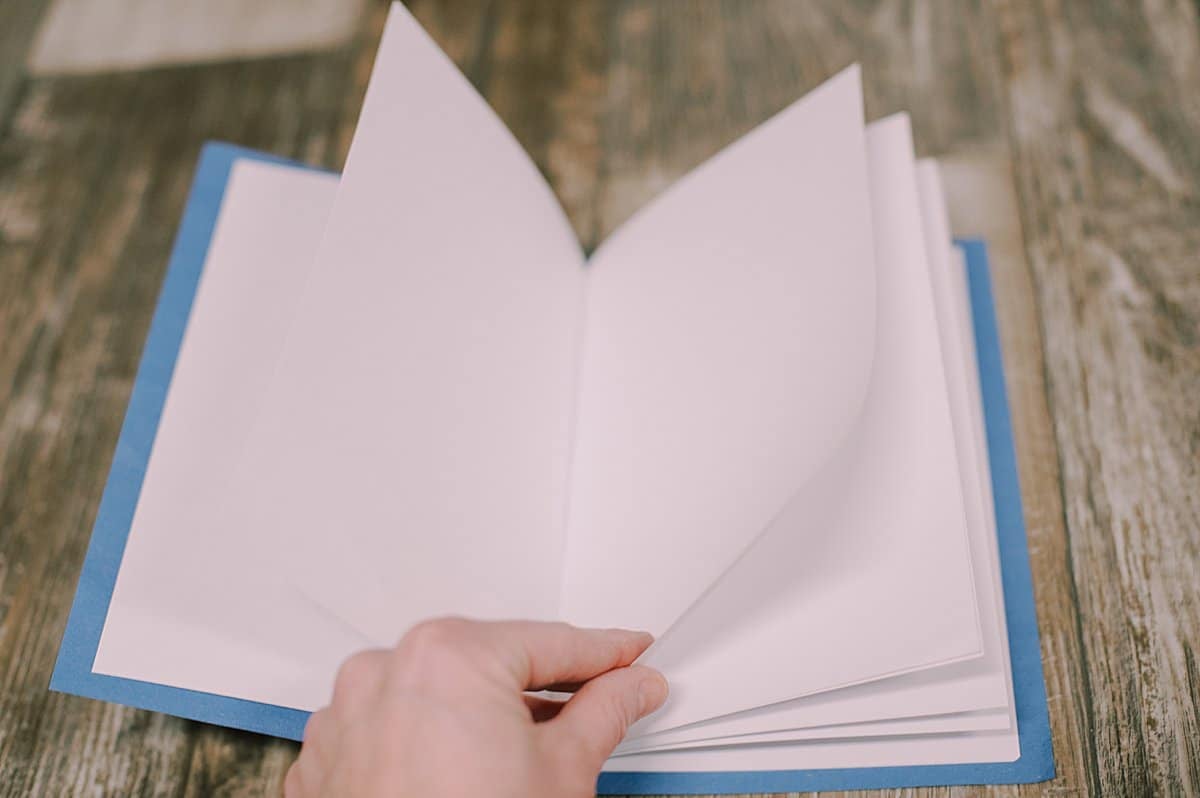 White printer paper pages on the inside of a homemade paper book with a blue cover.