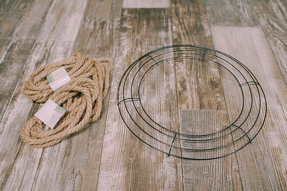 Supplies needed to make a wreath out of jute rope laying on a wooden surface.