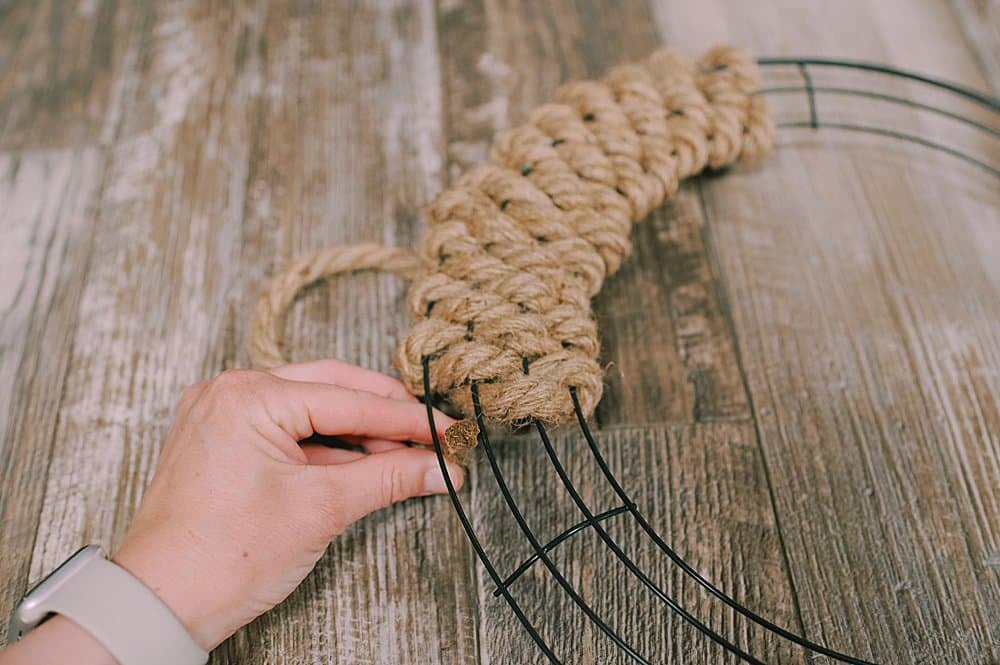 Showing the weaving of a jute rope into and out of a wire wreath form.