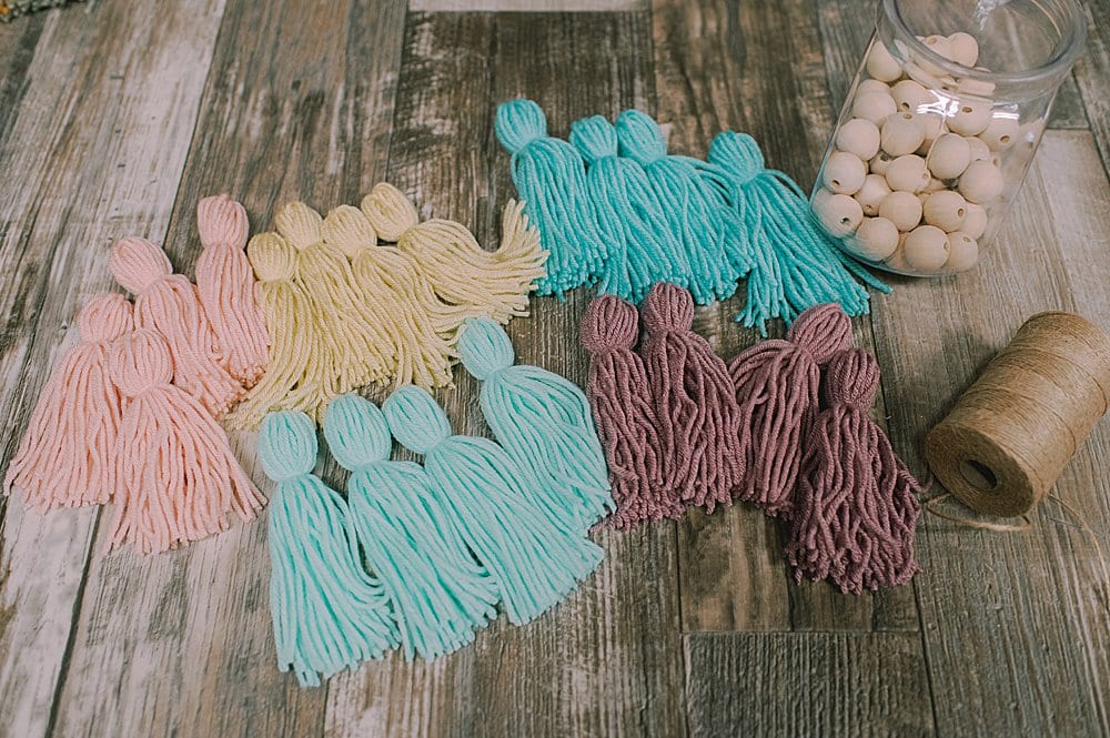 supplies to make a yarn tassel garland with pastel colors