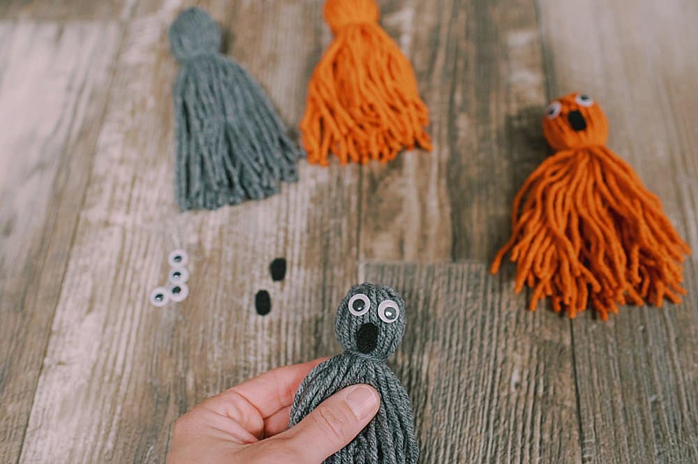 Learn how to make yarn tassel ghosts for Halloween using yarn, googley eyes, felt, and hot glue! They are super easy and a great kids craft!