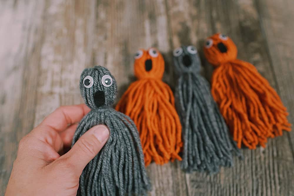 Learn how to make yarn tassel ghosts for Halloween using yarn, googley eyes, felt, and hot glue! They are super easy and a great kids craft!
