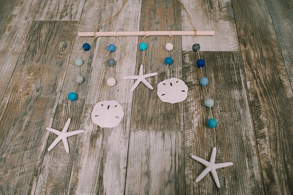 Learn how to make a DIY ocean wall hanging with plastic sand dollars and star fish from the Dollar Tree, plus felt balls and twine!