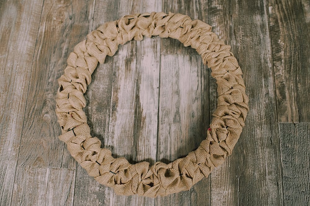 A completed burlap wreath laying on a wooden backgroud.